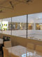 Na sliki so okna, ki imajo požarno zasteklitev brez profilov Promat®-SYSTEMGLAS F1 60 v Pohištvenem centru Lesnina Koper, pred okni so v prostoru mize in stoli v restavraciji. 