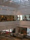 Pogled na velik prazen prostor skozi požarno odporno steklo brez okvirjev Promat®-SYSTEMGLAS F1 60 v Pohištvenem centru Lesnina v Kopru. V zgornjem delu slike so jeklene bele konstrukcije. 