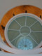 Okrogla horizontalno zastekljena konstrukcija s požarnimi stekli PROMAGLAS® v galeriji Nedbalka v Bratislavi - pogled od zgoraj na belo konstrukcijo in stekleno notranjost. V ozadju rjav parket v prostorih galerije. 