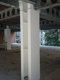 Primer jeklenega stebra, zaščitenega z intumescenčno belo barvo PROMAPAINT®-SC3, nad stebrom pa jeklene sive konstrukcije v praznem nedokončanem prostoru med prenovo. 