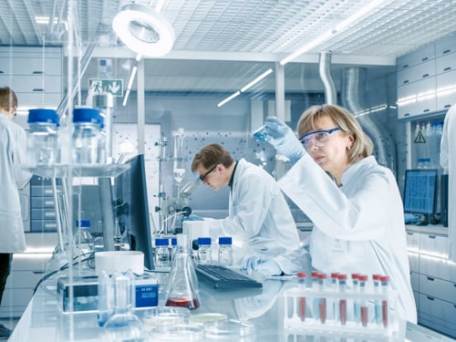 Naučnici u zaštitnim naočarama rade u naučnoj laboratoriji uz pomoć instrumenata i pribora poput epruveta i hemikalija.