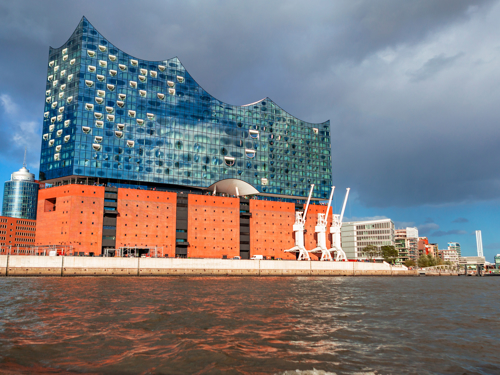 Ogromna moderna zgradba je postavljena na obrežju reke. Spodnji del zgradbe je rdeče barve, zgornji del pa stekleno modre barve z valovito odrezano streho. 