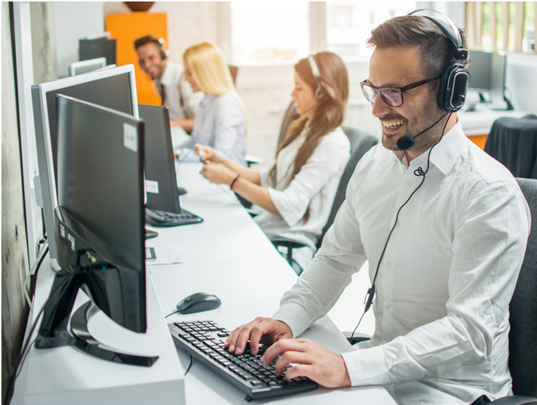 Muži a ženy sedia pri počítačoch v call centre so sluchátkami a mikrofónmi.