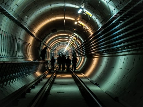 Na slici je skupina inženjera koji provjeravaju instalacije u nedovršenom tunelu.