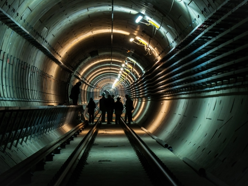 Imagine cu muncitori într-un tunel luminat